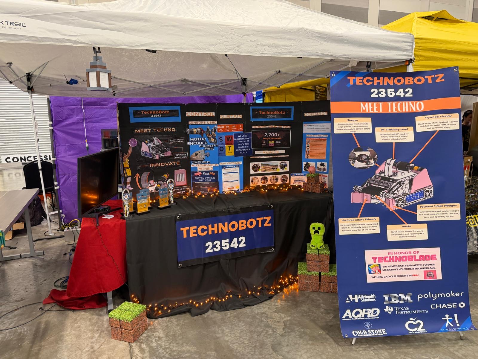 The TechnoBotz pit at a competition: banners reading 23542, sponsor logos, display boards and game pieces on the table
