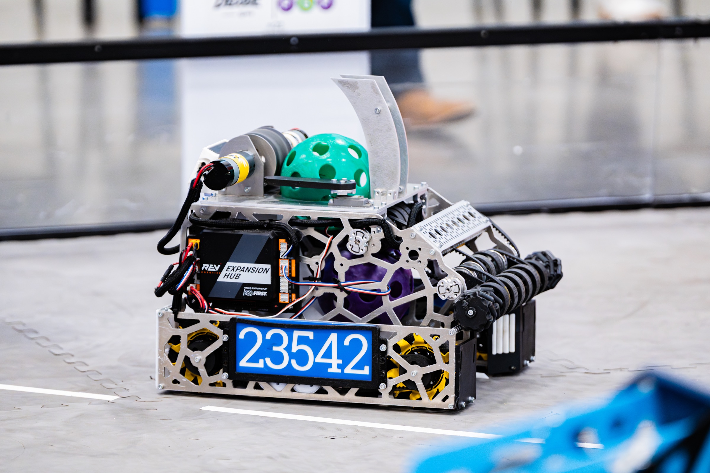 The robot Porkchop on the competition field, a green game ball in its intake above the 23542 number plate